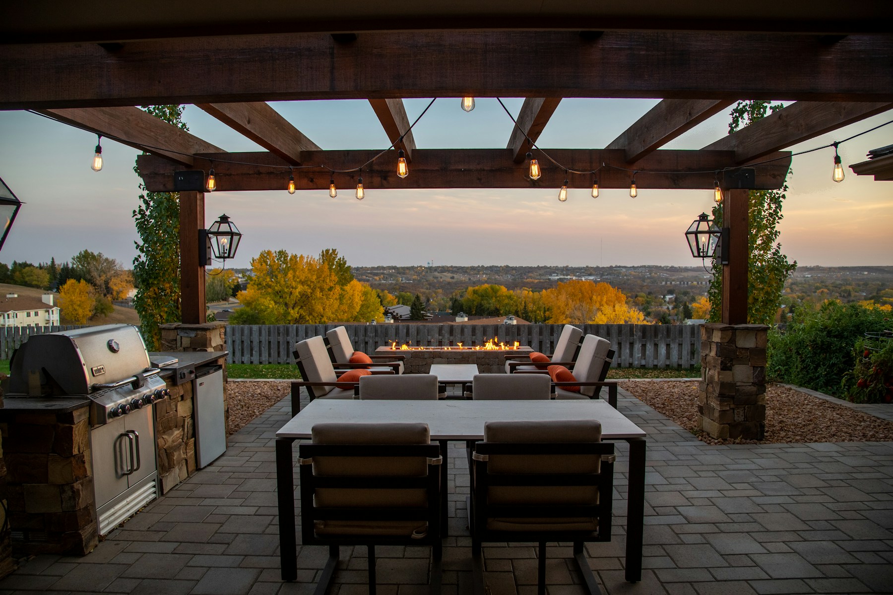 A backyard patio with outdoor dining and lounge furniture under a pergola