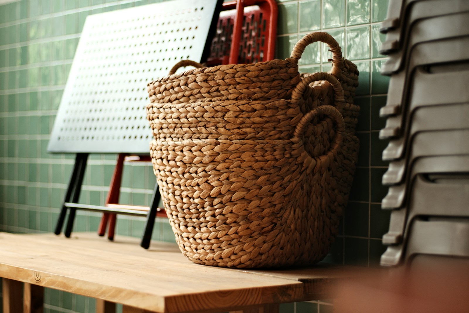 A large woven storage basket with handles on a wooden shelf